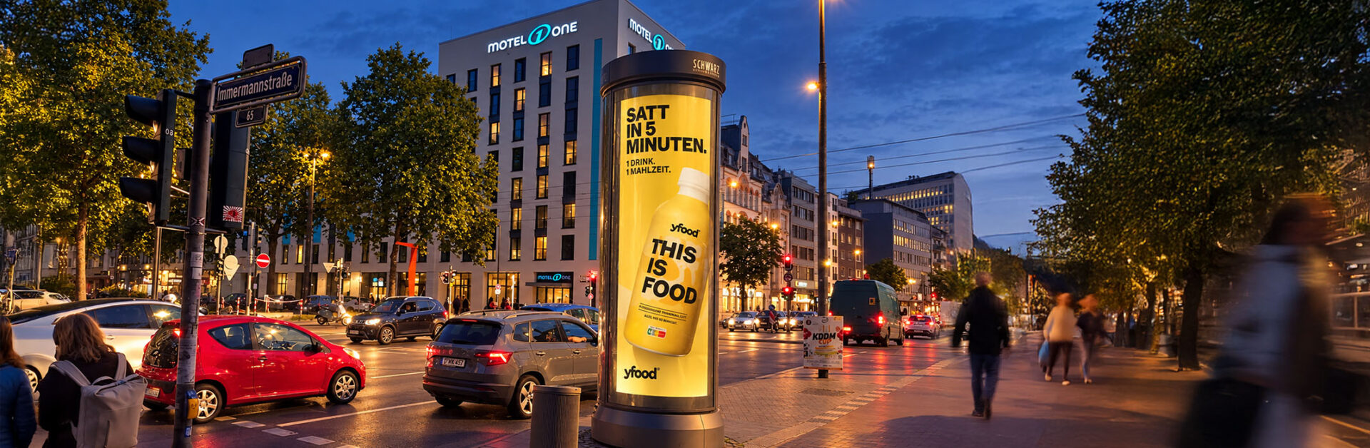 Beleuchtete Premium Citylight-Säule von Schwarz Außenwerbung mit yfood-Kampagne in Düsseldorf bei Nacht