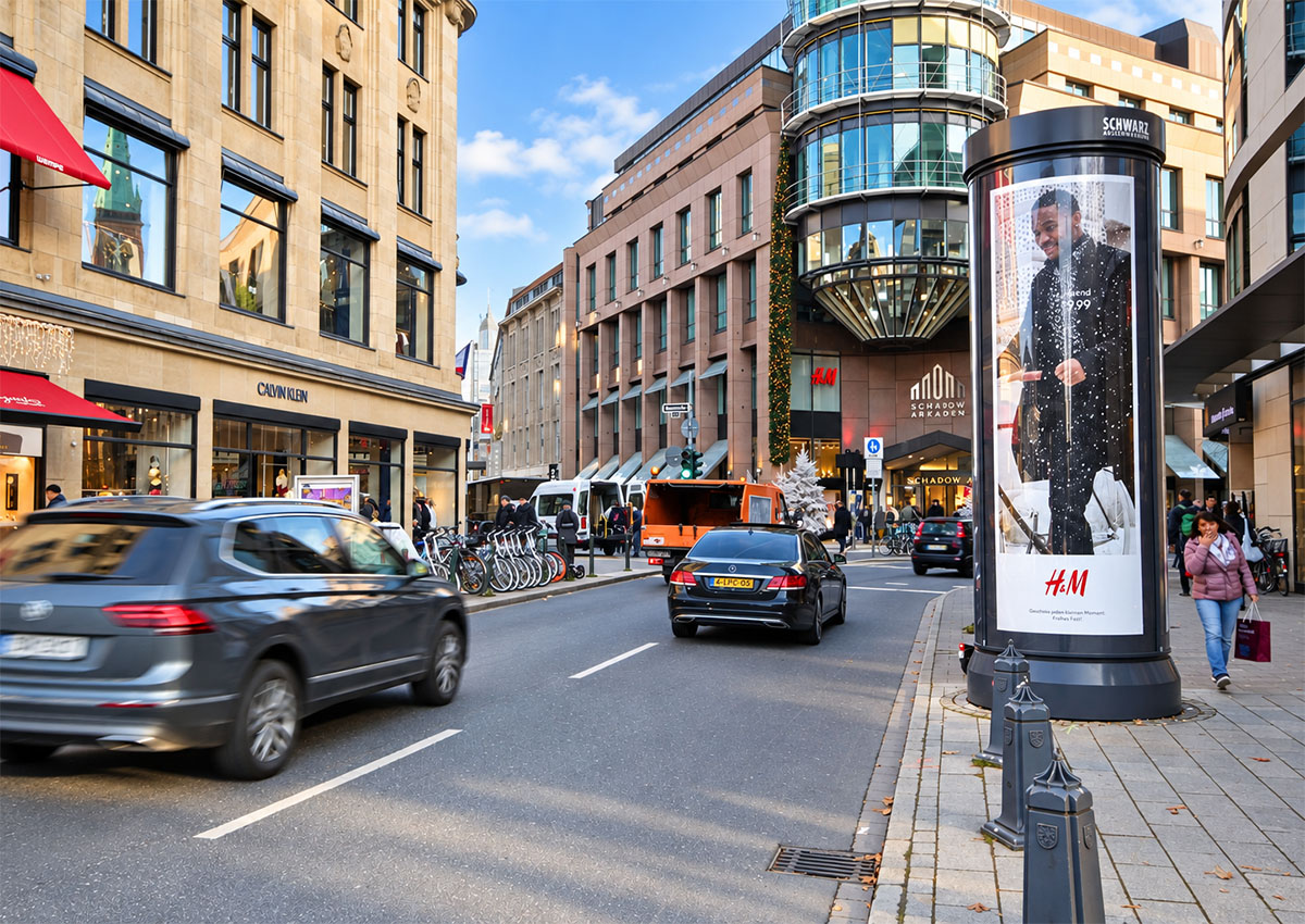 Premium Citylight-Säule von Schwarz Außenwerbung mit H&M-Kampagne in Düsseldorf bei Tag